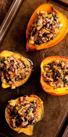 three stuffed squash halves with meat and vegetables in them on a baking sheet, ready to be cooked