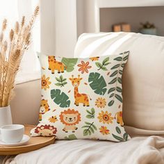 a white couch sitting next to a window with a pillow on top of it and a cup in front of it