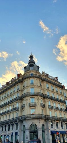 a large building with many windows and balconies on the top floor, next to a busy street