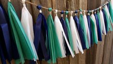 some tassels are hanging from a line on a wooden fence with blue, white and green ribbons