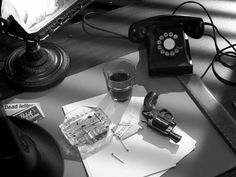 an old fashioned telephone sitting on top of a desk next to a glass of water