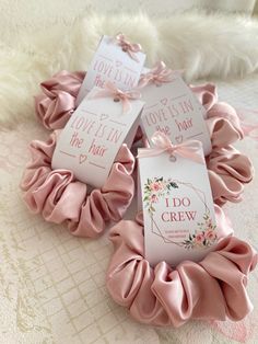 three pink scrunffles with tags attached to them on a white bed sheet