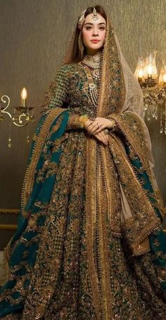 a woman in a green and gold bridal gown standing next to a chandelier