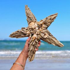 a starfish made out of driftwood is held by a person's hand