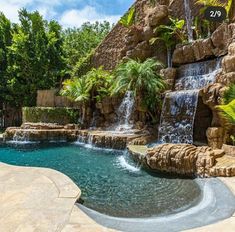 an outdoor pool with waterfall and water features surrounded by rocks, palm trees and other tropical plants