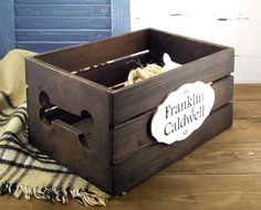 a wooden crate sitting on top of a wooden floor next to a blanket and a blue door