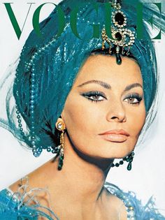 a woman with green hair and jewelry on the cover of a magazine, wearing an elaborate headpiece