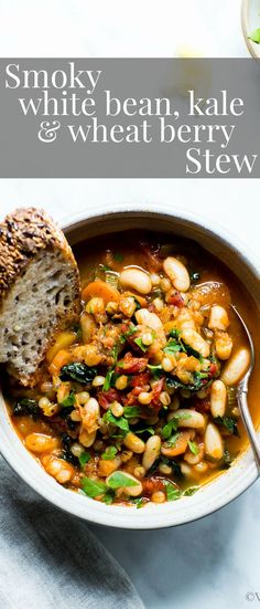 a bowl filled with beans and greens next to a piece of bread