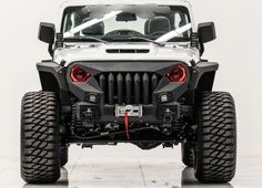 the front end of a white jeep with large tires