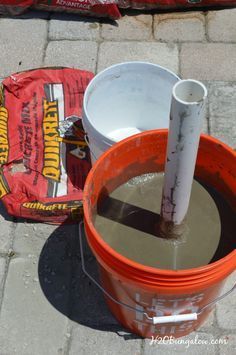 an orange bucket filled with water next to a bag of chips and a red bag