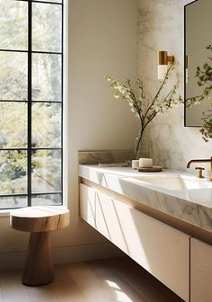 a bathroom with marble counter tops and two sinks in front of a large window that looks out onto the trees outside