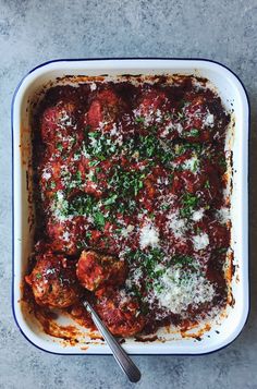 a casserole dish with meatballs and parmesan cheese