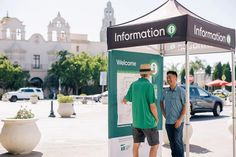 two men standing under an information booth