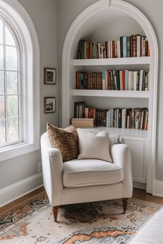 a white chair sitting in front of a book shelf filled with books