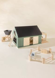 a toy house with a ladder to the roof next to it and a small wooden horse stable