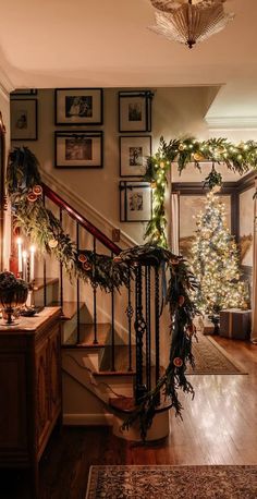 a staircase decorated for christmas with greenery on the bannister and wreaths