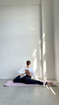 a woman sitting on a yoga mat in the middle of a room