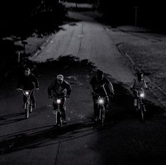 three people riding their bikes down the street at night with flashlights in their hands