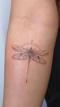 a small dragonfly tattoo on the arm