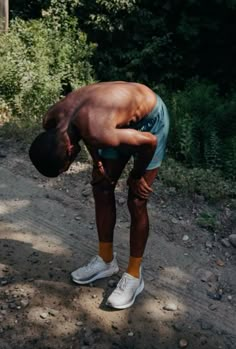 a man is bent over on the side of a dirt road