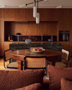 a wooden table sitting in the middle of a living room next to a kitchen area