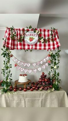 a table topped with lots of cupcakes under a red and white checkered canopy