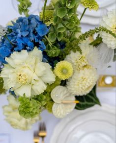 a vase filled with blue, white and green flowers on top of a wooden table