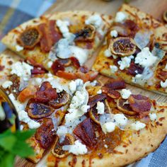 a close up of a pizza on a wooden cutting board with cheese and toppings