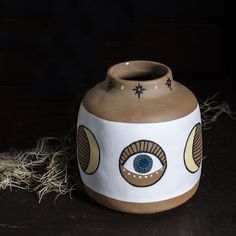 a brown and white vase with an eye painted on it