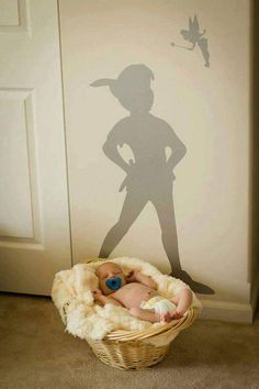 a baby in a basket next to a wall with a shadow of a person on it