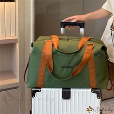 a person is pulling a green and white suitcase with orange straps on it's handle