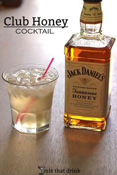 a bottle of jack daniels sitting next to a glass filled with ice and a straw