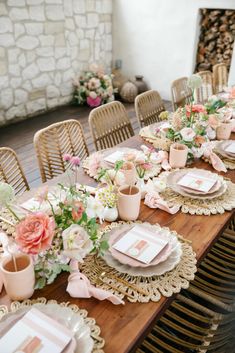 the table is set with pink and gold plates, napkins, and flower centerpieces