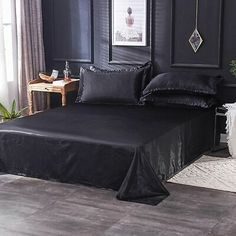 a bed with black sheets and pillows in a room