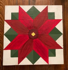 a red and green flower is painted on a wood paneled wall or table top