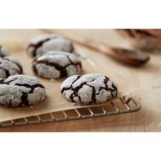 chocolate crinkle cookies on a cooling rack next to a bowl of powdered sugar