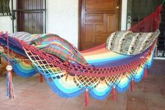 a multicolored hammock with tassels hanging from the ceiling in front of a door