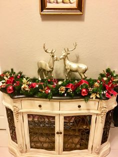 a white dresser with christmas decorations and deer figurines on it's top