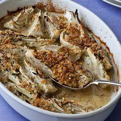 a white bowl filled with artichokes covered in sauce and crumbs