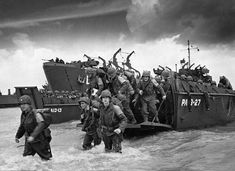 a group of men walking across a body of water next to a boat with soldiers on it