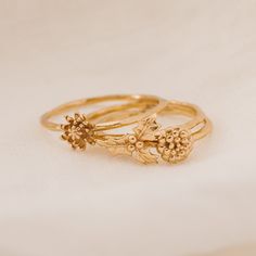 three gold rings with flowers on them sitting next to each other in front of a white background