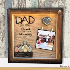 a wooden frame with some rocks and a photo on it that says dad, our rock is the world