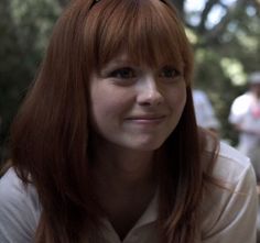 a woman with long red hair and glasses on her head is smiling at the camera