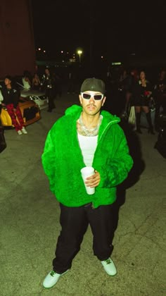 a man in a green jacket is holding a cup