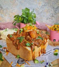 a piece of bread with meat and vegetables on it sitting on top of a newspaper