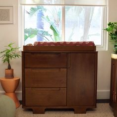 a baby's crib in the corner of a room with potted plants