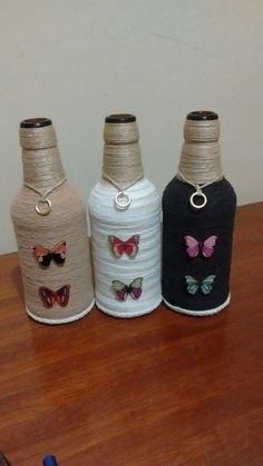 three bottles with butterflies on them sitting on a table