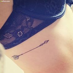 an arrow tattoo on the back of a woman's left side ribcage