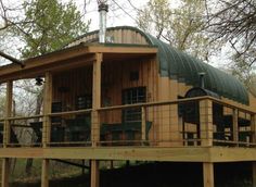 a wooden house with a green roof and metal balconies on the front porch