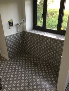 an empty bathroom with tiled floors and large window overlooking the trees in the distance is shown